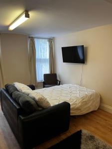 um quarto com uma cama, um sofá e uma televisão de ecrã plano em Entire Apartment boutique king size bed near Town Centre em Colchester