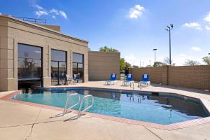 a swimming pool with chairs and a building at Comfort Inn & Suites in Wichita