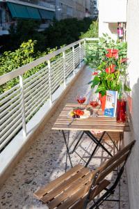 einen Holztisch mit Weingläsern und Blumen auf dem Balkon in der Unterkunft Blue Ark Acropolis Compass in Athen