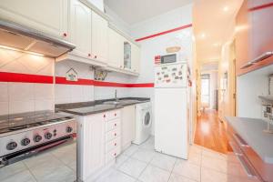 eine Küche mit weißen Geräten und einem roten Streifen an der Wand in der Unterkunft GuestReady - Spring break in Lisbon in Lissabon