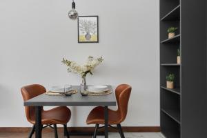 a dining room table with chairs and a vase of flowers at Rent like home - Spacious Studio with Balcony Słonimskiego 2 in Wrocław