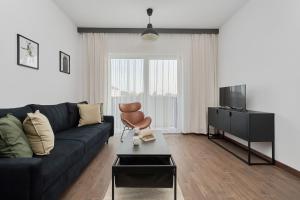 a living room with a black couch and a television at Rent like home - Spacious Studio with Balcony Słonimskiego 2 in Wrocław