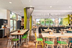 um restaurante com mesas de madeira e cadeiras verdes em Vienna House Easy by Wyndham Wuppertal em Wuppertal