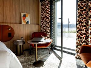 a hotel room with a bed and a table with a laptop at Pullman Lyon in Lyon