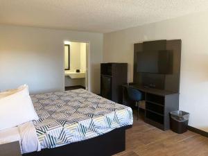 a bedroom with a bed and a desk with a television at Motel 6 Hurricane, WV in Hurricane