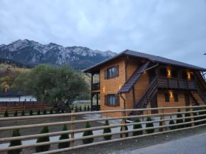 a wooden house with mountains in the background at Apartamente Creasta Craiului in Zărneşti