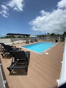 eine Terrasse mit Stühlen und ein Pool an einem Haus in der Unterkunft Les Terrasses de Vinty 3 villas autour d'une piscine in Sainte-Rose
