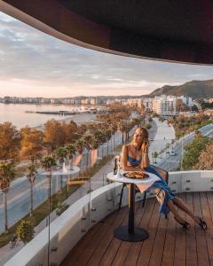 a woman sitting at a table on the balcony of a building at Yacht Hotel in Vlorë