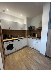 a kitchen with white cabinets and a washing machine at Appartement Louise in Le Havre