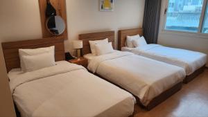 a hotel room with two beds and a mirror at Heyy Seogwipo Hotel in Seogwipo