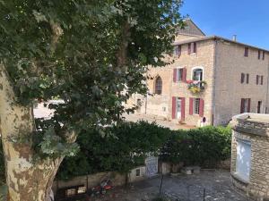 um grande edifício de pedra com uma árvore em frente em Maison de village avec 2 jardins em Pernes-les-Fontaines