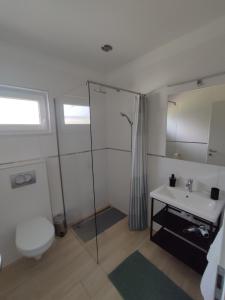een badkamer met een douche, een toilet en een wastafel bij Katáng Vendégház 