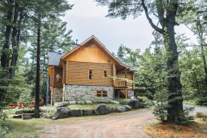 una cabaña de madera en el bosque con un camino de tierra en Chalet Authentik 50 - Hot tub, Pools, Lake & Resort, en Mille-Isles