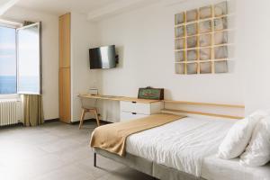 a bedroom with a bed and a desk and a window at Cà de Mâ - Sea Front Suite in Genoa