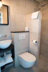 a bathroom with a white toilet and a sink at Hotel Aan Zee in Noordwijk aan Zee