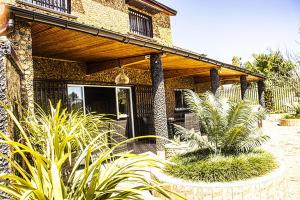 a house with a porch with plants in front of it at Hôtel restaurant le MIAMIAM GLOUGLOU in Ambositra