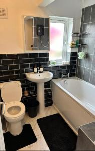 a bathroom with a toilet and a sink and a tub at The Maison- Cozy home stay in Nottingham