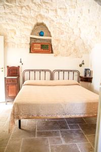 - une chambre avec un lit et un mur en pierre dans l'établissement Trullo Dany, à Locorotondo