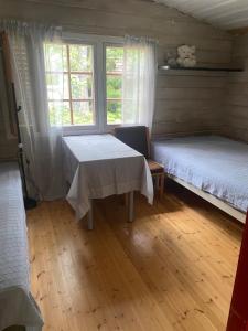 Habitación con 2 camas, mesa y ventana en A cosy cottage in Norrtälje, en Norrtälje