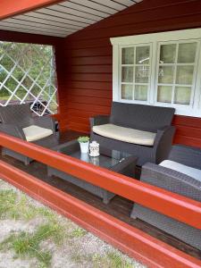 un porche con 2 sillas de mimbre y una mesa en A cosy cottage in Norrtälje, en Norrtälje