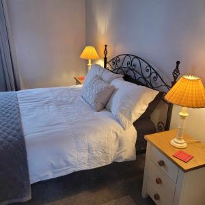a bedroom with a bed with white sheets and two lamps at LITTLE HAVEN 1 Bedroom House sought after area in Topsham