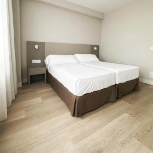 a bedroom with a large bed with white sheets at Hotel El Águila in Utebo +34 photos