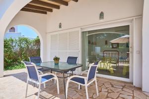 a patio with a glass table and chairs on a patio at Villa Acebuche in Cala d´Or