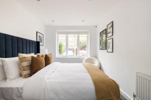 a white bedroom with a large bed and a window at The Walworth Hideout - Elegant 2BDR Flat in London