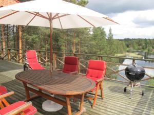 une table en bois avec des chaises et un parasol sur une terrasse dans l'établissement Holiday Home Nedre Gärdsjö - DAN086 by Interhome, à Rättvik