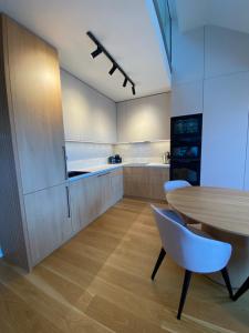 uma cozinha com uma mesa de madeira e armários brancos em Molo Lipno apartmán B232 em Lipno nad Vltavou
