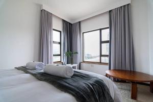 een slaapkamer met een bed, een tafel en ramen bij Ocean Wave No.1 Self Catering in Swakopmund