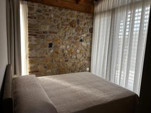 a bed in a bedroom with a stone wall at Nuovo B&B Colline San Benedetto in Marostica