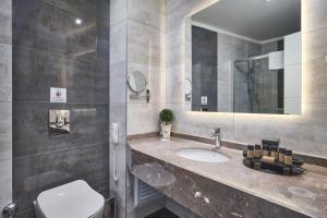 ein Badezimmer mit einem Waschbecken, einem WC und einem Spiegel in der Unterkunft Litore Resort Hotel & Spa - Ultra All Inclusive in Okurcalar