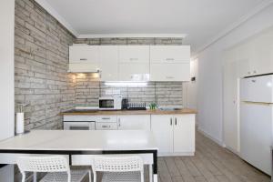 a kitchen with white cabinets and a table and chairs at Apartment at 30 mts from sea in Playa de las Americas