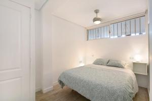 a white bedroom with a bed and a window at Apartment at 30 mts from sea in Playa de las Americas +22 photos