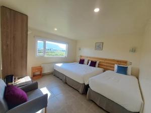 1 dormitorio con 2 camas, sofá y ventana en Hotel Casa Verde, en Puerto Natales