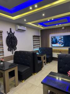 una sala de espera con muebles de cuero negro y TV en MITOS LUXURY SUITES (BODE THOMAS), en Lagos