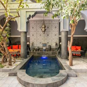 a swimming pool in a building with trees and furniture at Riad des Mile Nuits in Marrakesh