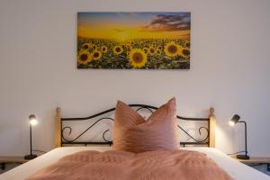 ein Bett mit einem Bild eines Sonnenblumenfeldes in der Unterkunft Pension Haus am Picho in Arnsdorf