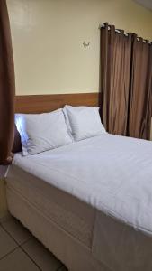 łóżko z białą pościelą i poduszkami w pokoju w obiekcie Saymon Hotel w mieście Portel