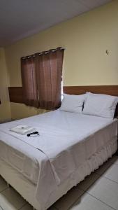 a large bed with white sheets and pillows at Saymon Hotel in Portel