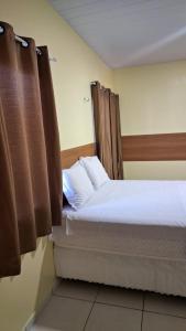 a bedroom with a bed with white sheets and brown curtains at Saymon Hotel in Portel