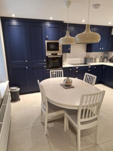 uma cozinha com armários azuis e uma mesa e cadeiras brancas em Ryan's Cottage em Rostrevor