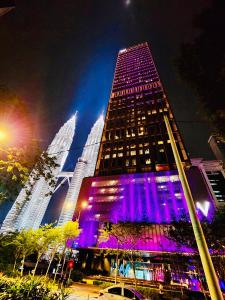 a tall building with purple lights on it at night at Tropicana Residence Klcc @ Roof Top Swimming Pool in Kuala Lumpur