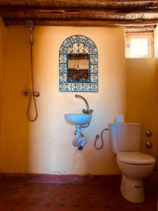 a bathroom with a toilet and a sink on a wall at Camp M'hamid Ras N'khal in Mhamid