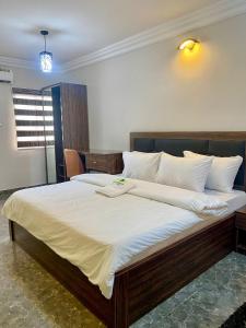 MOK Apartments & Suites في لاغوس: غرفة نوم بسرير كبير مع شراشف بيضاء