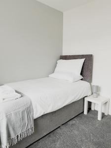 a white bedroom with a bed and a side table at Duxford House by Blue Skies Stays in Middlesbrough