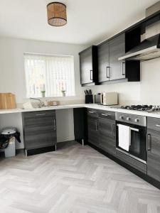 a kitchen with black cabinets and a white floor at Duxford House by Blue Skies Stays in Middlesbrough