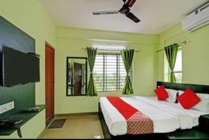 1 dormitorio con 1 cama con almohadas rojas y TV en Goroomgo Green Oasis Inn Kolkata en Pānchuria