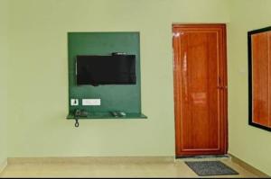 Telewizor na ścianie obok drzwi w obiekcie Goroomgo Green Oasis Inn Kolkata w mieście Pānchuria